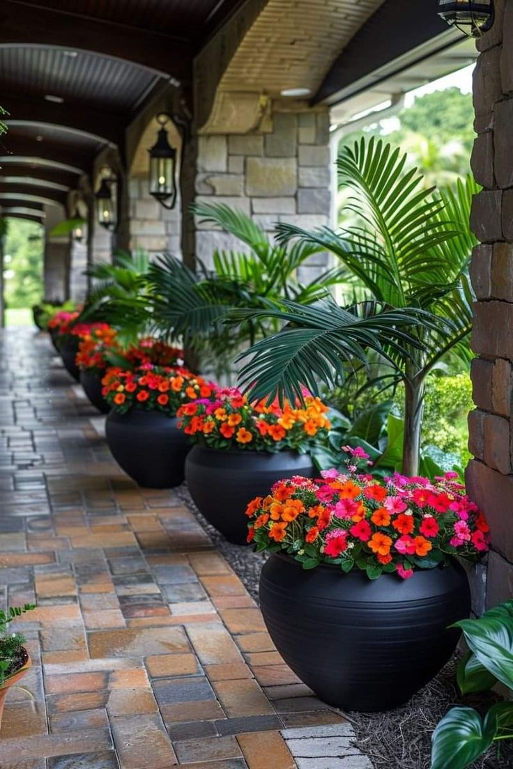 several large planters filled with colorful flowers on a brick walkway