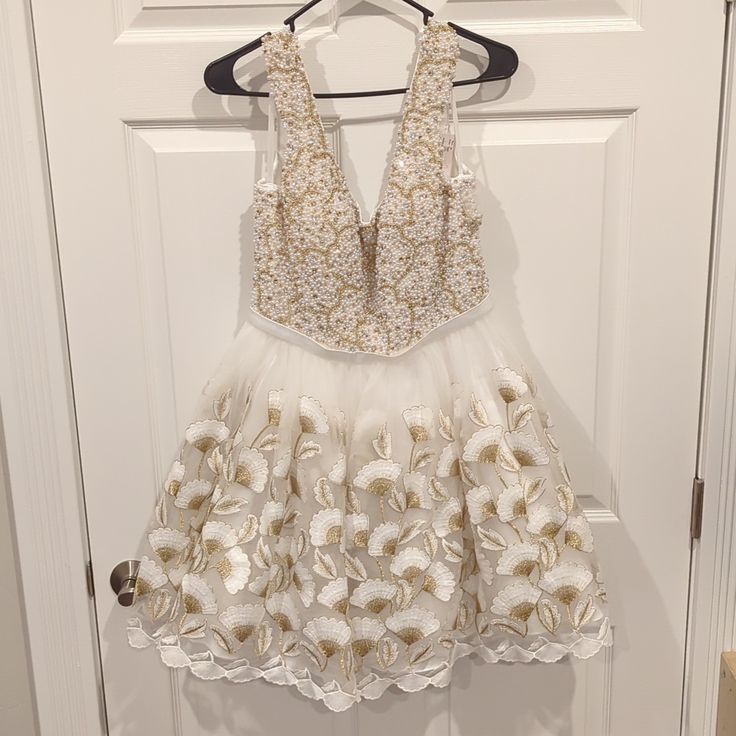 Mac Duggal White And Gold Beaded Dress. Soft U-Shaped Front And Back, Center Back Zipper. Never Worn, Still Has Tags! Stored In Dress Bag. Size: 10, Pit To Pit: 18", Waist: 30" Around, Shoulder To Hem: 35" Smoke Free, Dog Friendly Home. Please Make An Offer! Create A Bundle To Get Further Discounts And Free Shipping! No Reasonable Offer Refused! Embellished V-neck Mini Dress For Wedding, White Embellished Mini Dress For Wedding, White Sleeveless Embellished Mini Dress, White Embroidered Lace Mini Dress, V-neck Embellished Mini Dress For Wedding, White Floral Embellished Mini Dress For Party, Elegant White Dress With Pearl Embroidery, White Embroidered Mini Dress For Party, Elegant Embroidered Dress For Homecoming