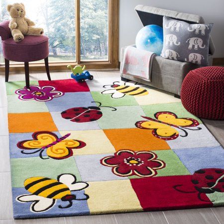 a child's room with a colorful rug and teddy bear on the floor in front of a window