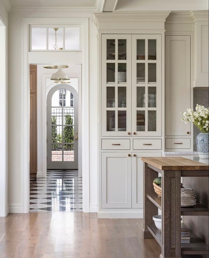 a large kitchen with white cabinets and wood flooring on the side walk leading to an entry way