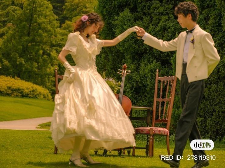 a young man and woman dressed in formal wear dancing on the lawn with their arms around each other