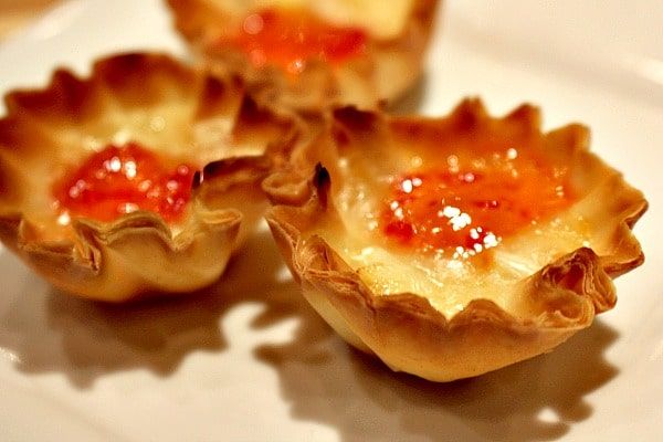 three small pastries on a white plate with ketchup in the middle,