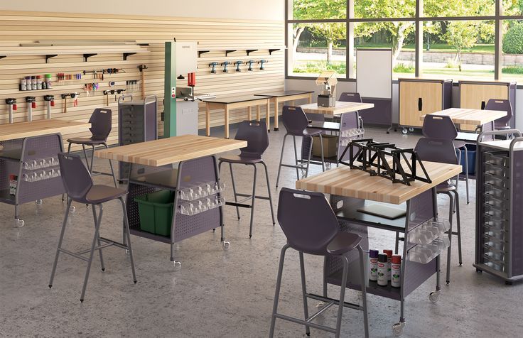 an empty classroom with many desks and chairs in front of large windows that look out onto the park