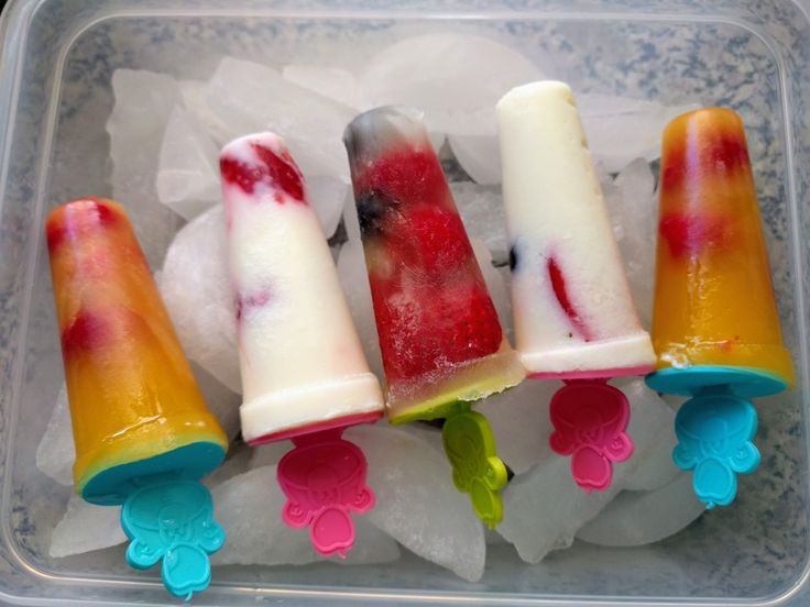 four popsicles are sitting on ice in a plastic container