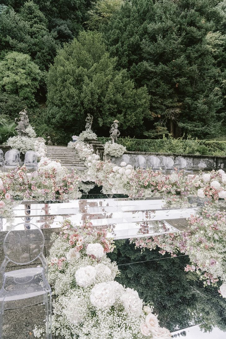 an outdoor garden with flowers on the ground and stairs leading up to trees in the background