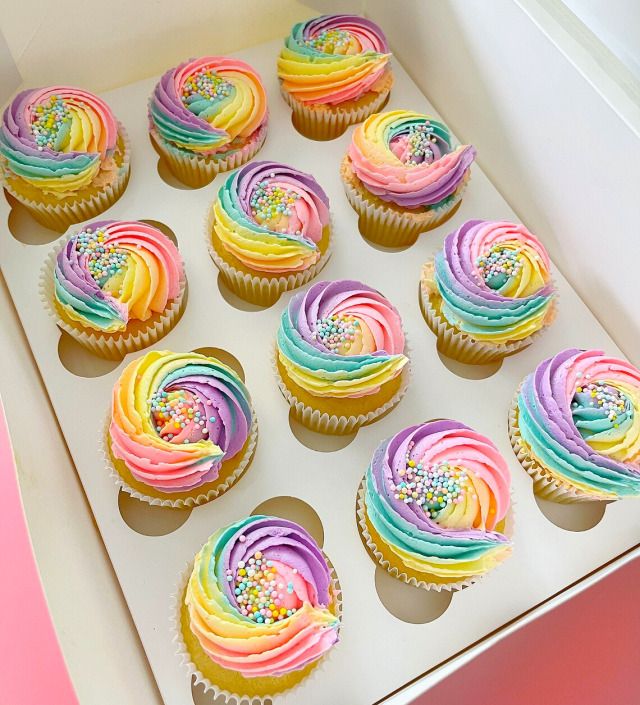 a box filled with cupcakes covered in rainbow frosting