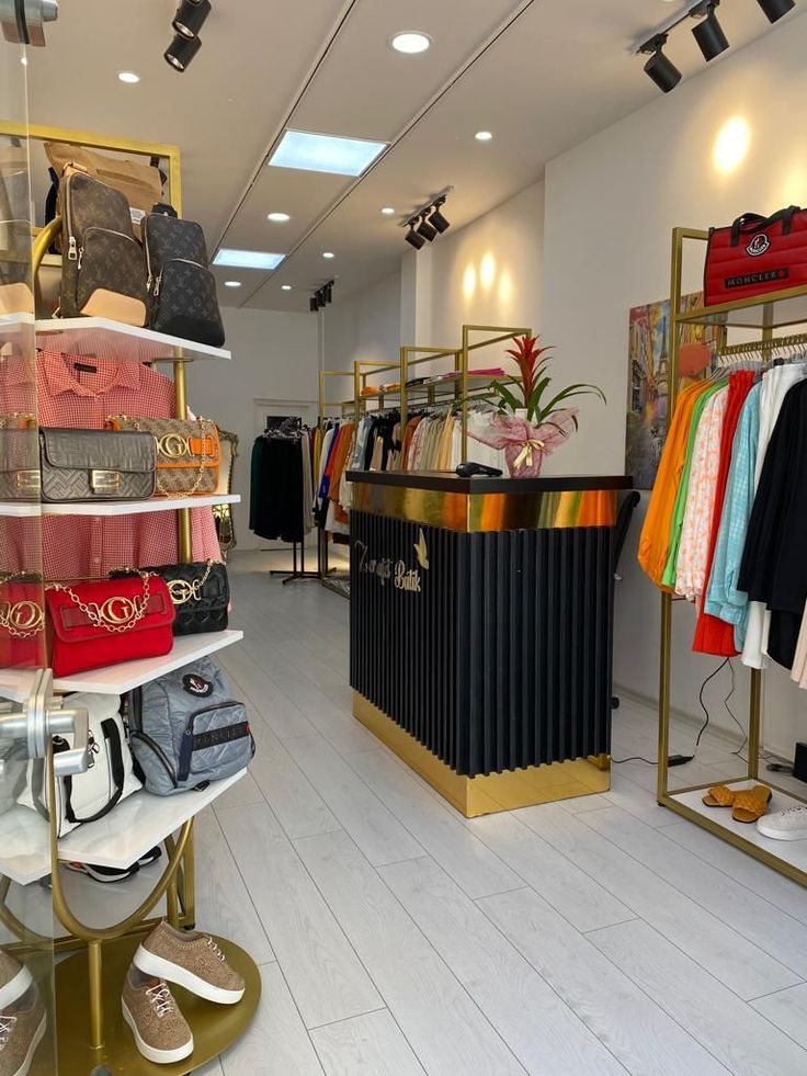 the inside of a women's clothing store with clothes and handbags on display