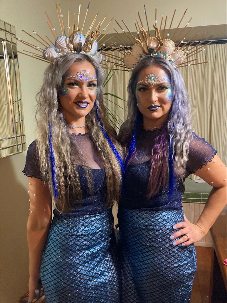 two women dressed in mermaid costumes pose for the camera with their hands on their hips