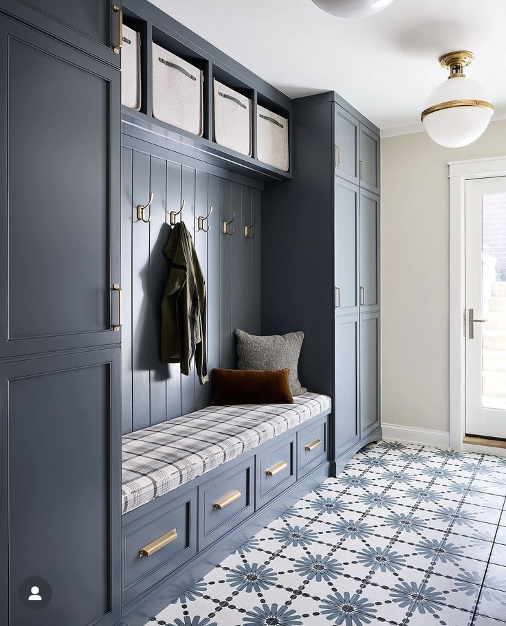 a room with blue cabinets and a bench in the corner, along with a coat rack