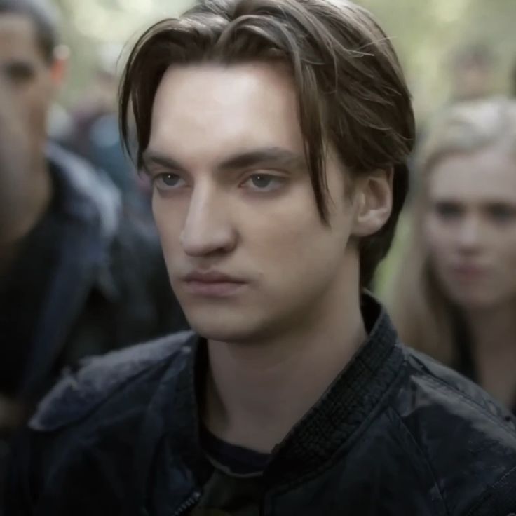 a close up of a person wearing a leather jacket with other people in the background