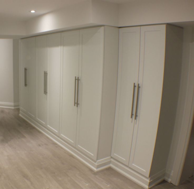 an empty room with white cupboards and wood flooring in front of the wall