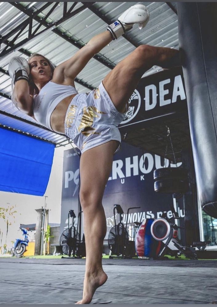 a woman kicking a ball in a gym