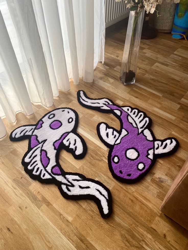 two purple and white rugs on the floor in front of a window with curtains