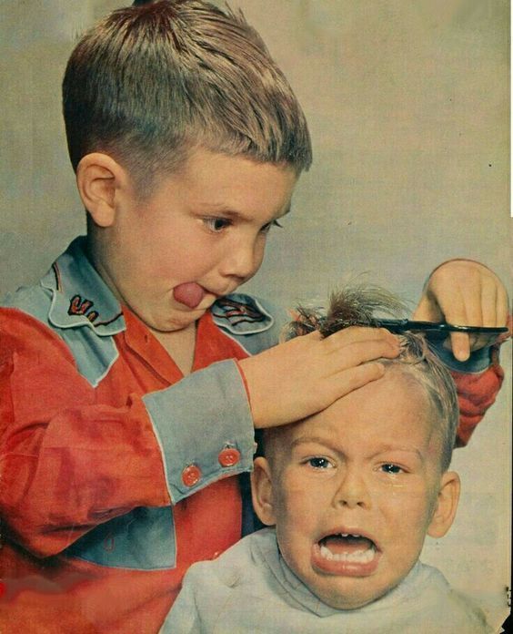 two young boys are having their hair cut