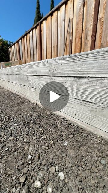 a wooden fence with rocks and gravel around it