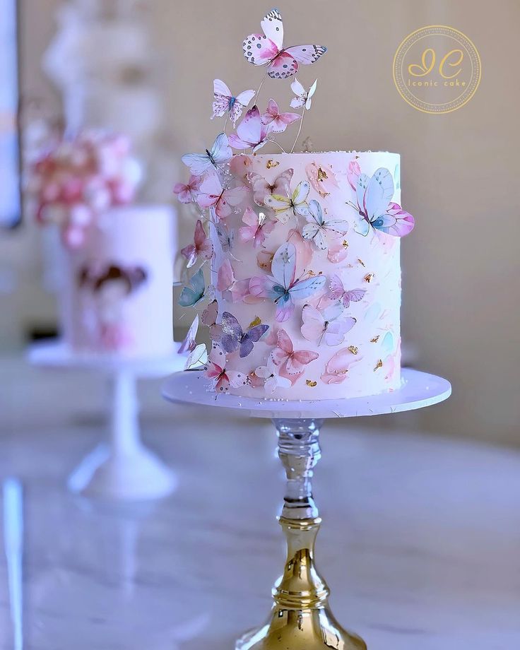 there is a pink cake with butterflies on it and two other cakes in the background