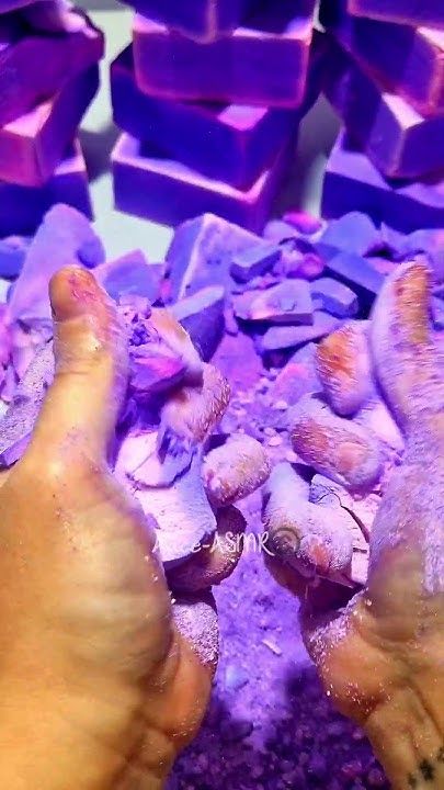 two hands are shown with their fingers on some purple rocks