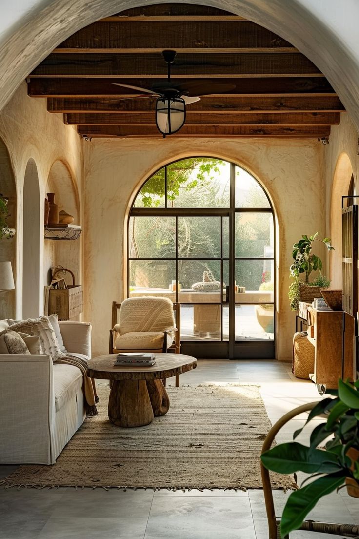 a living room filled with furniture and a large arched doorway that leads to an outside patio