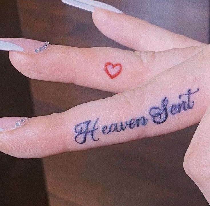 two fingers with tattoos on them that say heaven sent and heart in the middle,