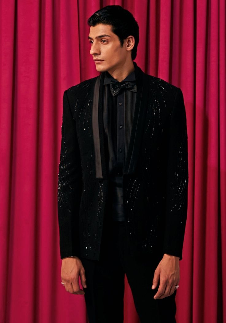 Step into sophistication with our Black Wave Embroidered Tuxedo Set. This exquisite ensemble features a shimmering textured blazer adorned with intricate hand-embroidered waves, paired with a crisp black pintuck shirt, bow tie, sash, and pants. Perfect for formal occasions like weddings, cocktail parties, or elegant dinners. Experience unparalleled style and elegance with our Black Wave Embroidered Tuxedo Set. Components : 5 (Blazer, Shirt, Bowtie, Sash and Pants) Composition : Textured Suiting Care: Dry Clean Only and Vacuum Storage This product can be customized for sleeves, length of blouse and neckline Delivery : 4-6 weeks as the product is hand crafted. Check Size Guide or choose MySize for free customisation (All Sizes above XL can be made at 15% additional cost) For more information Luxury Long Sleeve Tuxedo For Black-tie Events, Luxury Winter Tuxedo For Black-tie Events, Elegant Semi-formal Winter Tuxedo, Luxury Long Sleeve Blazer For Black-tie Events, Elegant Black Winter Tuxedo, Elegant Long Sleeve Tuxedo For Black-tie Events, Elegant Winter Suit With Shawl Collar, Elegant Shawl Collar Winter Suits, Luxury Embellished Long Sleeve Tuxedo