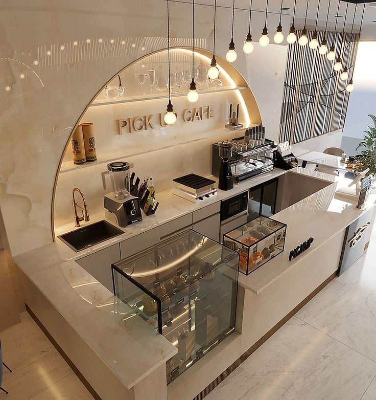 a kitchen with an oven, sink and counter top in the center is illuminated by hanging lights