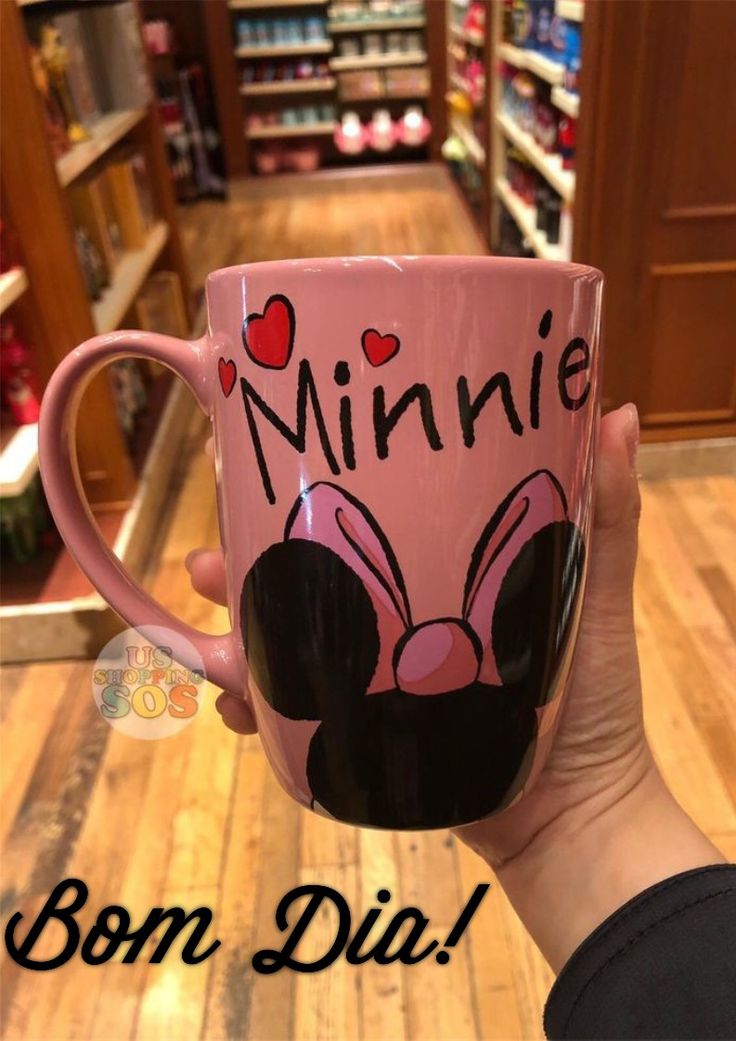 a person holding a pink coffee mug with minnie mouse on it in a store aisle