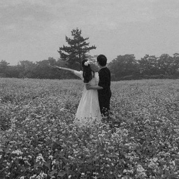 a man and woman standing in the middle of a field