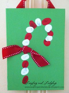 a handmade christmas card with a red ribbon and white dots on green paper, hanging from a wooden frame