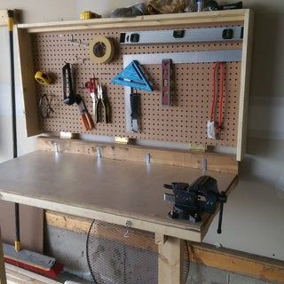 a workbench with many tools on it and pegboard attached to the wall