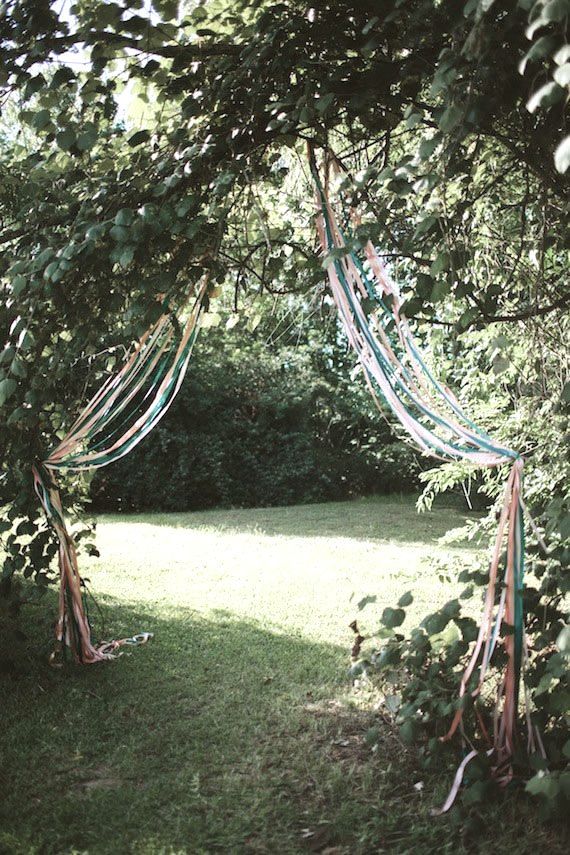 an outdoor area with grass, trees and ribbons hanging from the branches in front of it