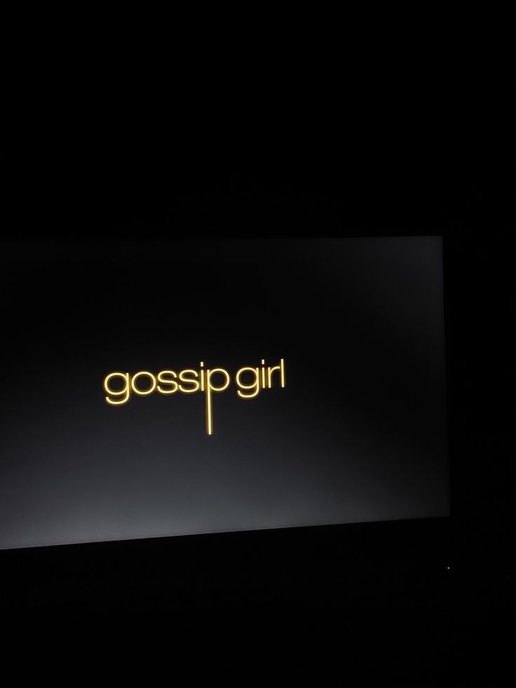 the logo for gossip girl is lit up on a black background in front of a dark backdrop