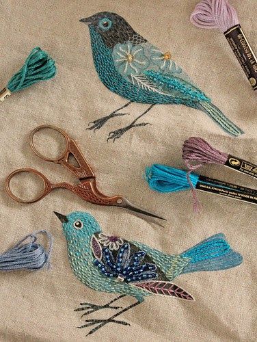 some scissors are laying next to each other on a table with different colored thread and beads