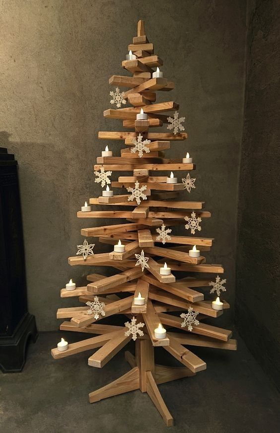 a wooden christmas tree made out of wood planks with candles on the bottom and snowflakes on top