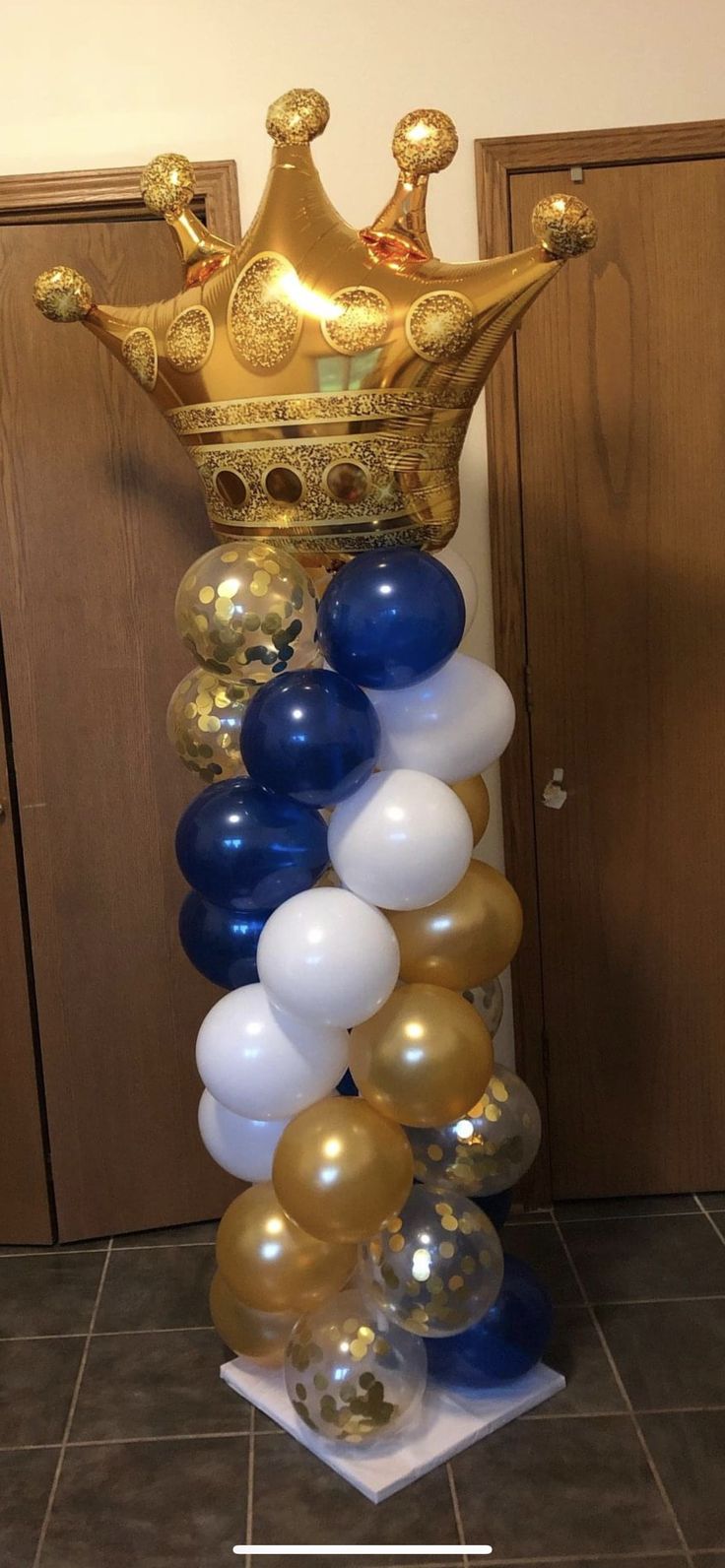 a tall gold crown with blue and white balloons