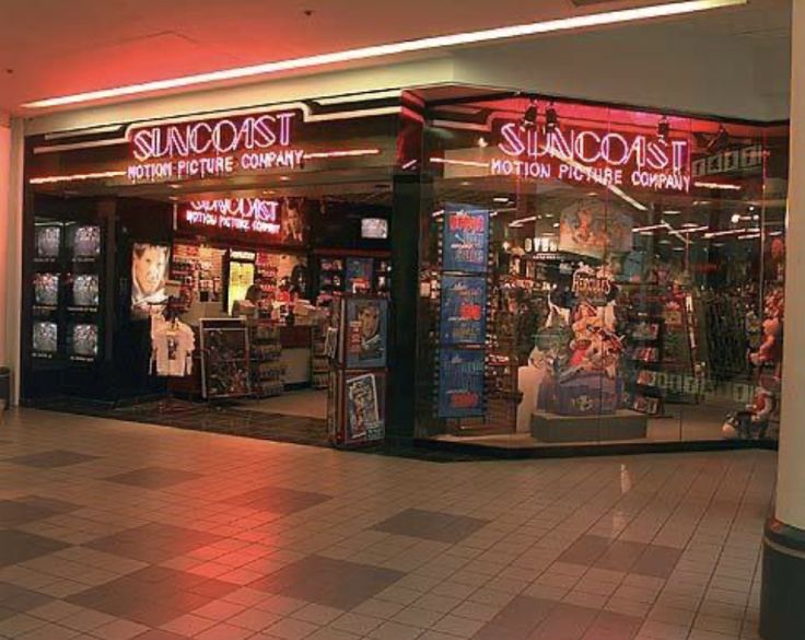 an empty shopping mall with the lights on and signs lit up in front of it