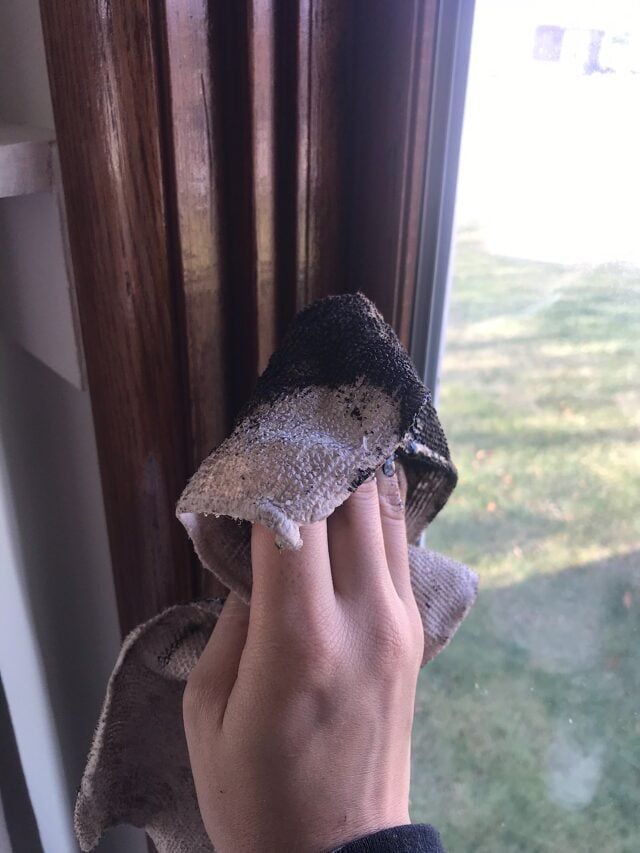 a person holding something in their hand near a window sill with grass and trees outside