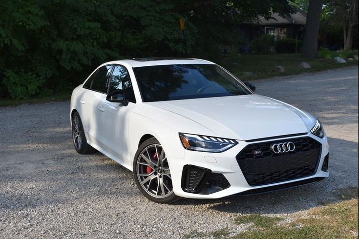 a white car parked on gravel next to trees