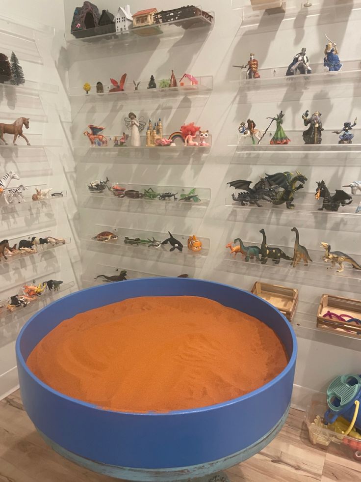 an orange substance in a blue bowl surrounded by toy figurines and toys on shelves