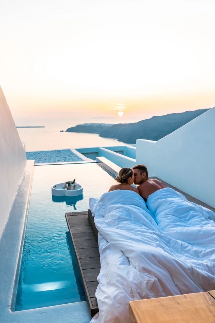 a man and woman laying in bed next to each other on the roof of a building