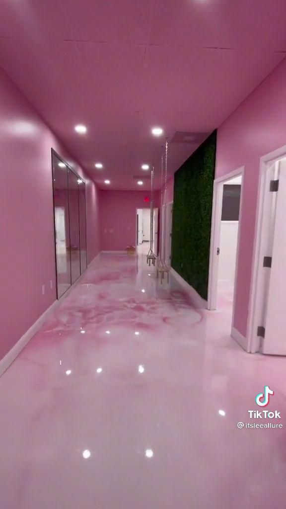 an empty hallway with pink walls and flooring in the center is lit by recessed lights