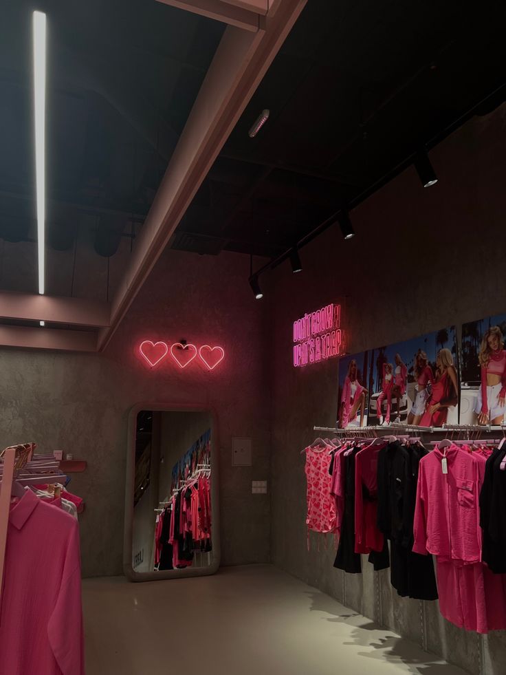 a clothing store with pink and black clothes on display in front of a mirror that says love