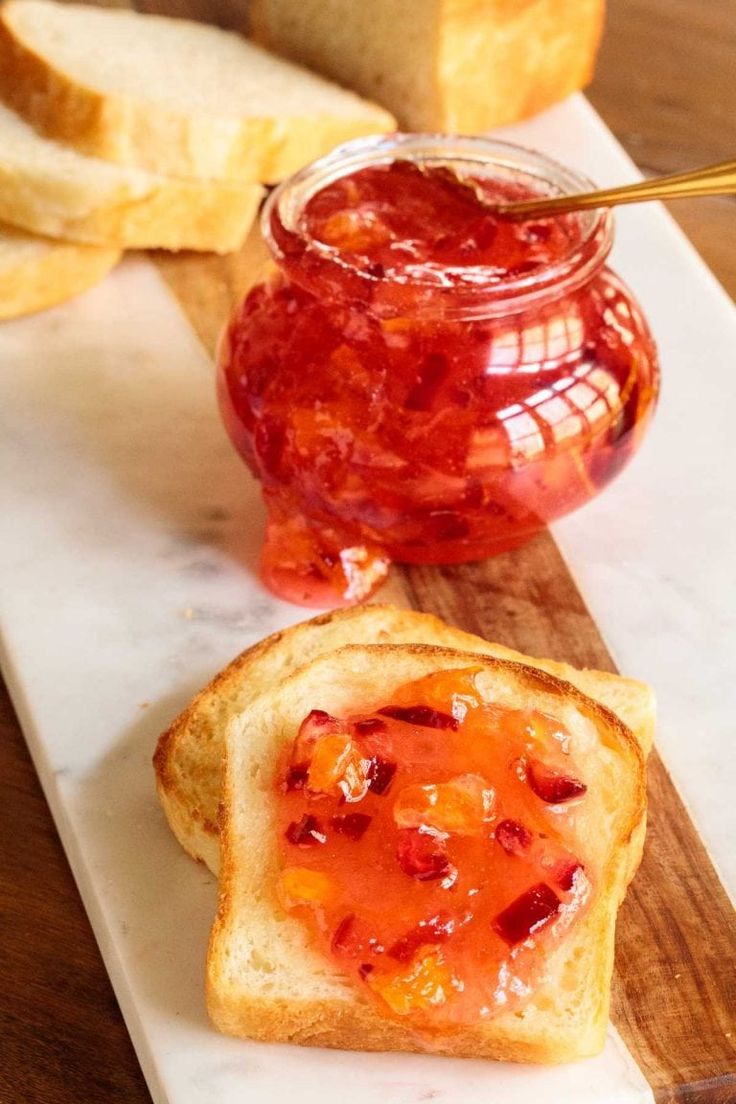 a piece of bread with jam on it next to a jar of jelly and some slices of bread