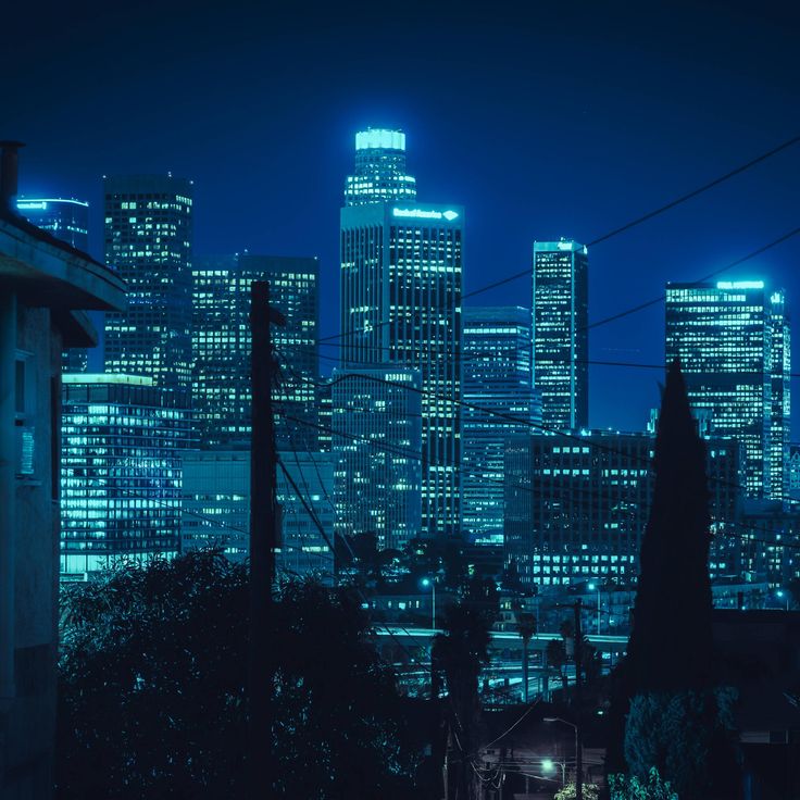 the city skyline is lit up at night with bright blue lights in the dark sky