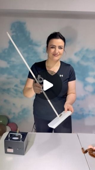 a woman standing behind a table holding a white object with two large metal poles in front of her