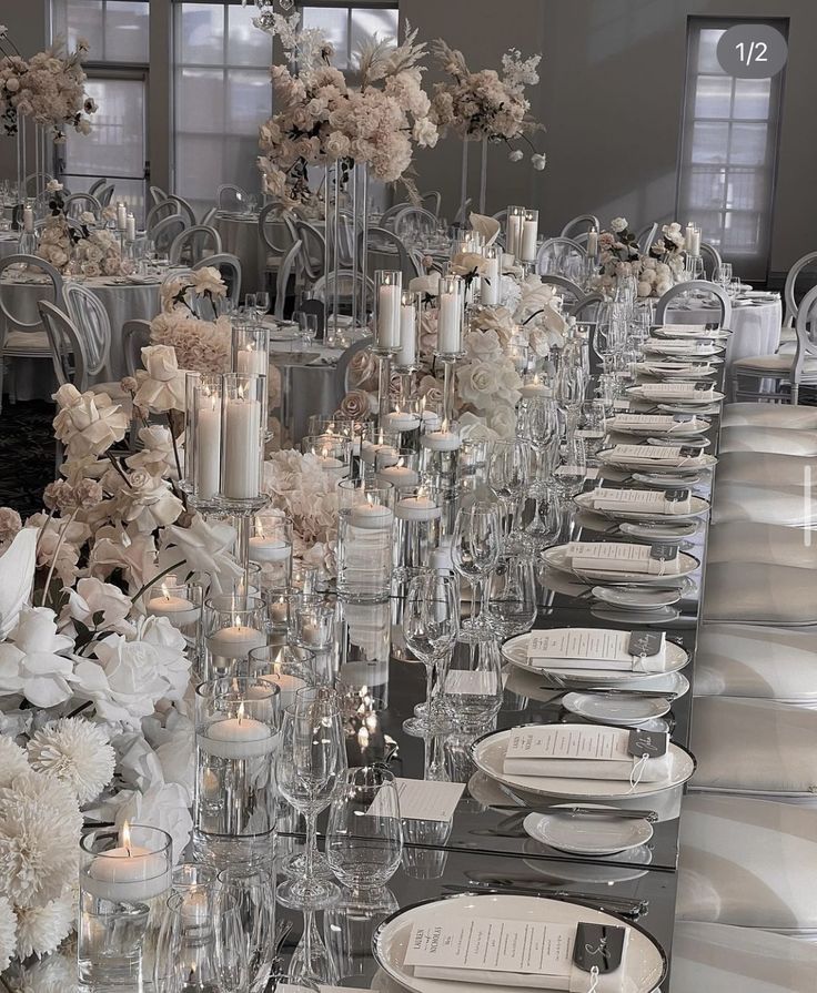 a long table is set with white flowers and candles for an elegant dinner party or special event