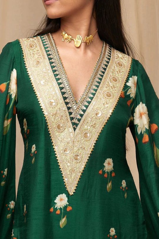 Print: Buttercup Color: Bottle Green Product Type: Kurta Fabric: Raw Silk No. of Components: 1 Details: Pick this Bottle Green Raw Silk kurta with V-neck to dazzle at a special occasion! Embellished with embroidered borders, the outfit features bell sleeves and side slits. Fit: Fitted Styling: Pair it with our statement jewellery and comfortable heels Disclaimer:The actual print-placement of the product may vary slightly from the image shown. Wash Care: Strictly dry clean only for digitally prin V Neck Kurti Design, Raw Silk Kurta, Printed Kurti Designs, Suit Neck Designs, Cutwork Lace, Stylish Kurtis Design, Buttercup Flower, Silk Kurti, Neck Designs For Suits