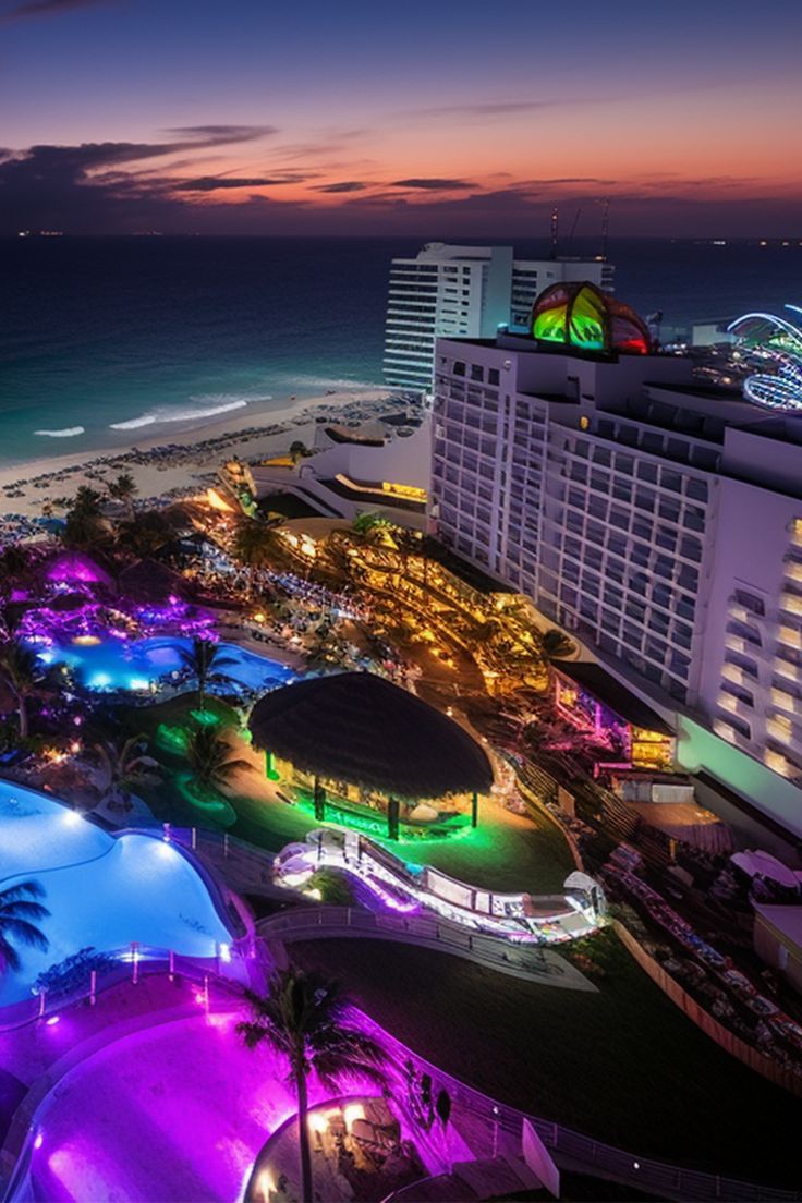 an aerial view of the beach and hotels at night with colorful lights in the foreground