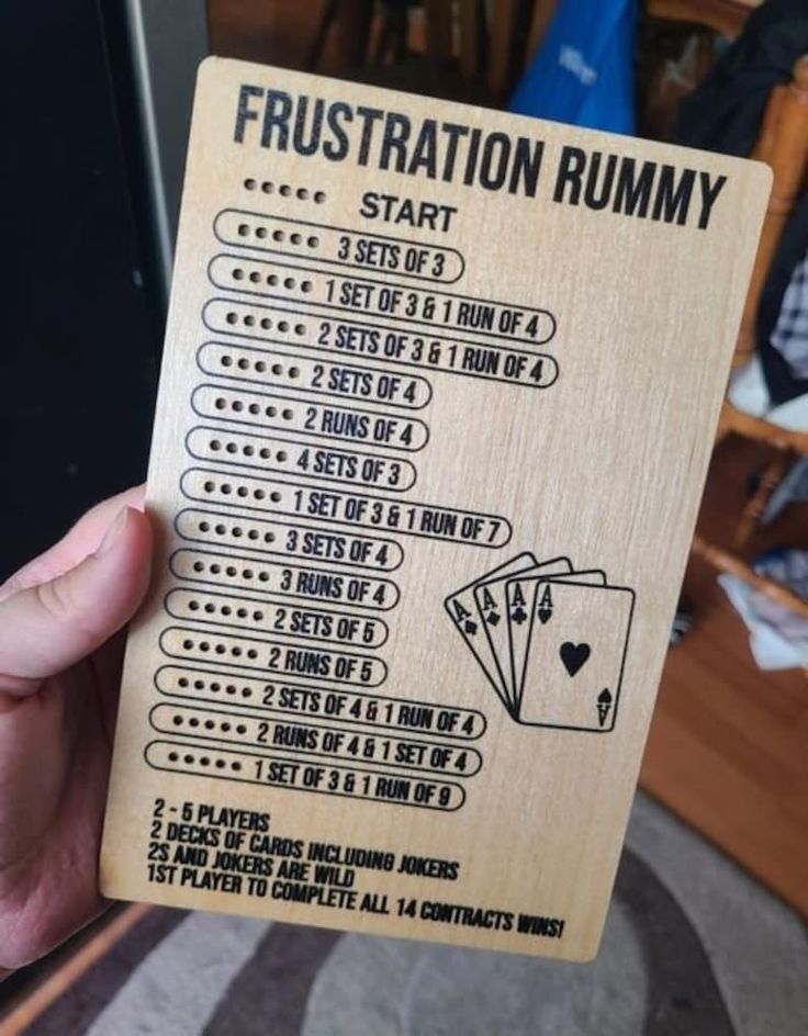 a person holding up a wooden card with instructions for how to play the rummy game