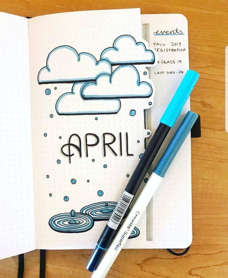 an open notebook with the word april written on it and two pens laying next to it