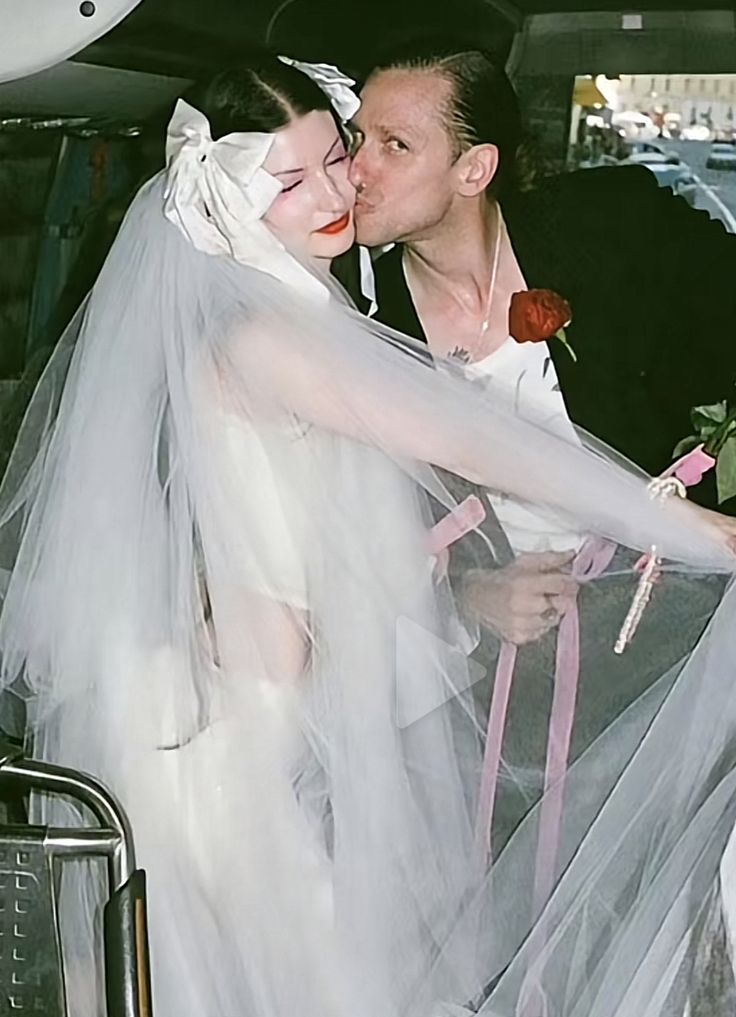 a man and woman kissing in the back of a car with veils over their faces